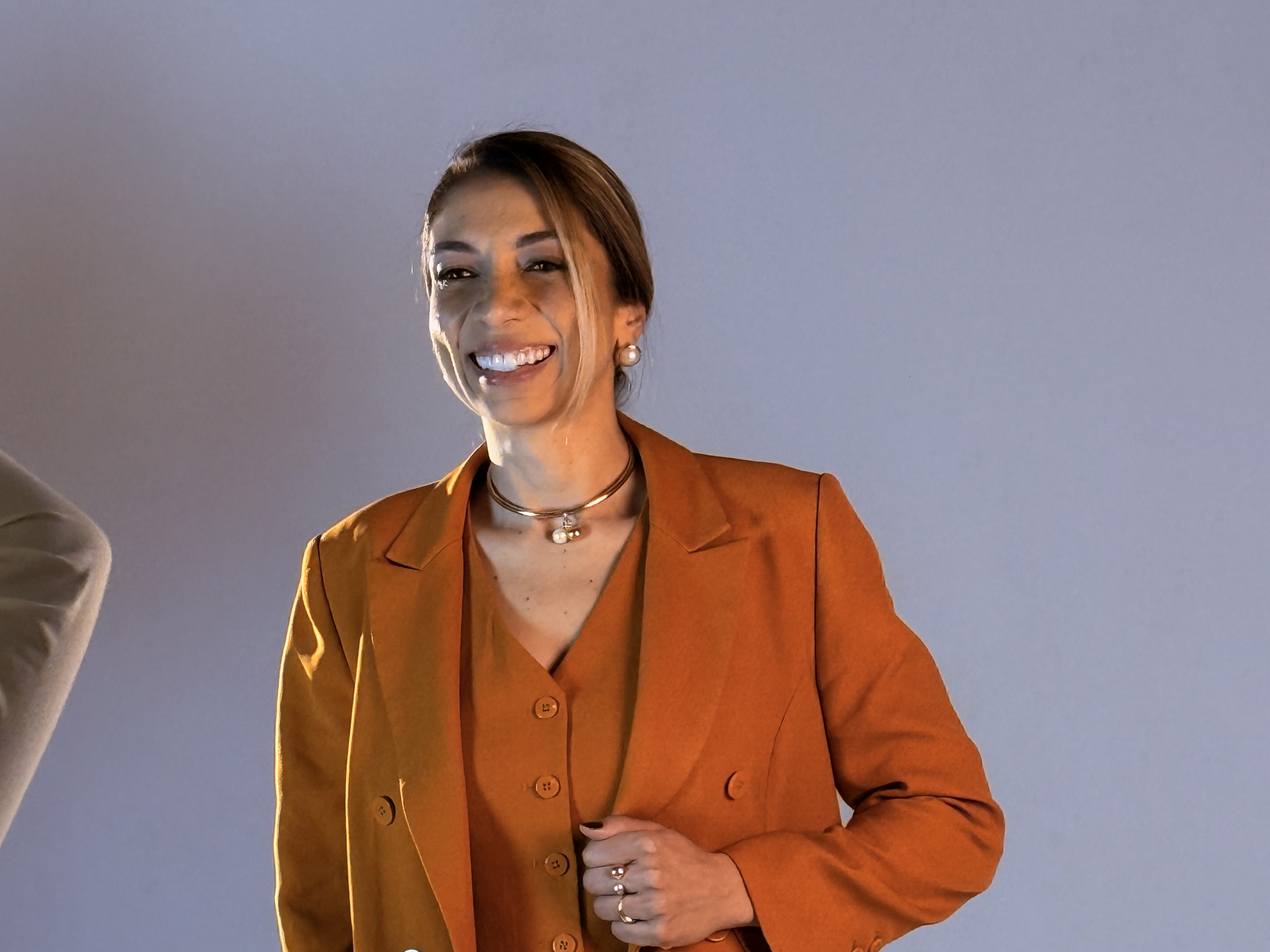 Retrato de Carla Modesto sorrindo, em alfaiataria mostarda.